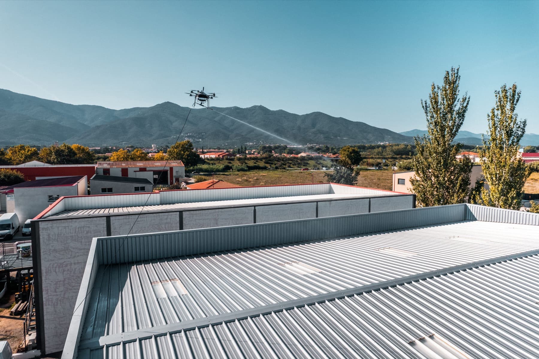 Drone traitant la toiture d'un bâtiment industriel, vue depuis le toit