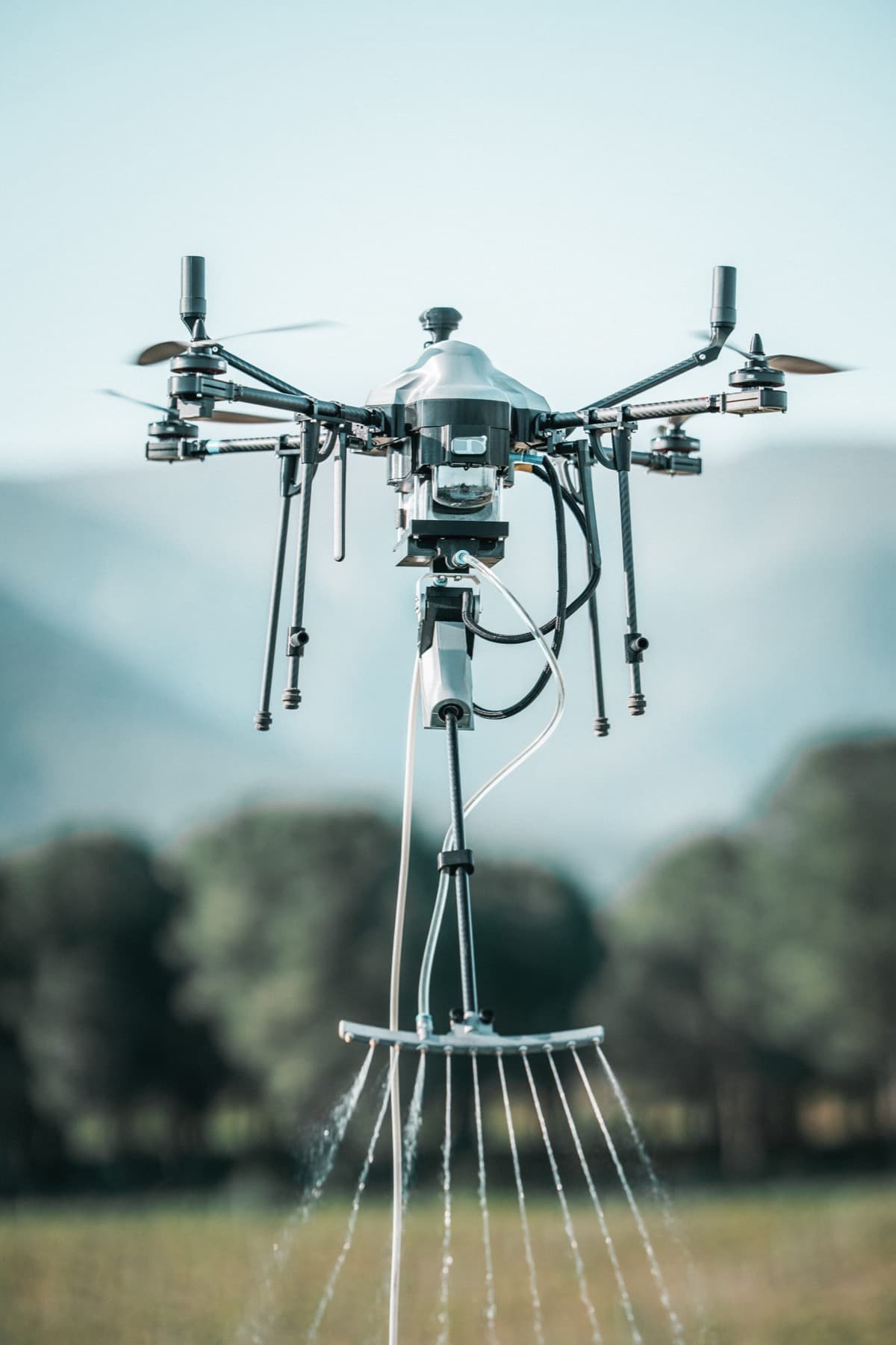 Drone technique en vol, rampe de pulvérisation active, montagnes en arrière-plan