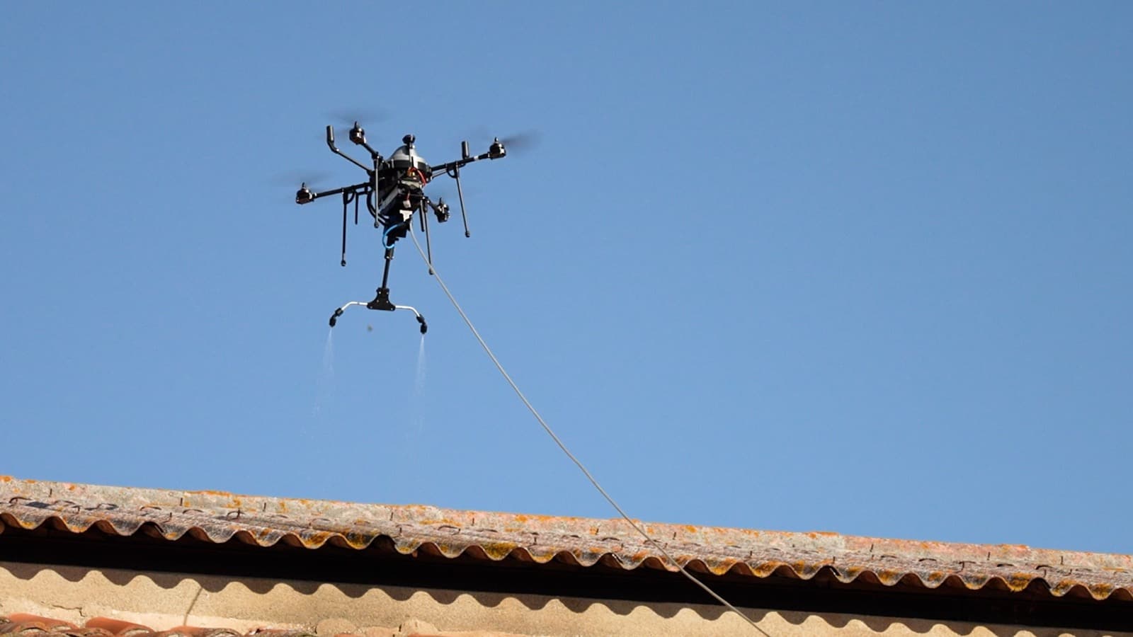 Drone en vol au-dessus d'une toiture en tuiles, traitement par pulvérisation